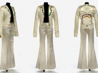 Jimmy Page Stage Outfit 1975. Currently displayed at the V&A Museum, London: Painted satin and gold cord. By Malcolm Hall. This stage costume, worn by Jimmy Page, of Led Zeppelin, is known as  the ‘Egyptian’ costume because of the symbols prominent on the back of the satin jacket. These symbols are more than just decoration, however, reflecting Page’s interest in the occult, and particularly the teachings of early 20th Century British occultist and writer Aleister Crowley. As well as having meaning in the symbols, the ivory satin costume itself would have been highly eye-catching, reflecting Page’s wild performance style.